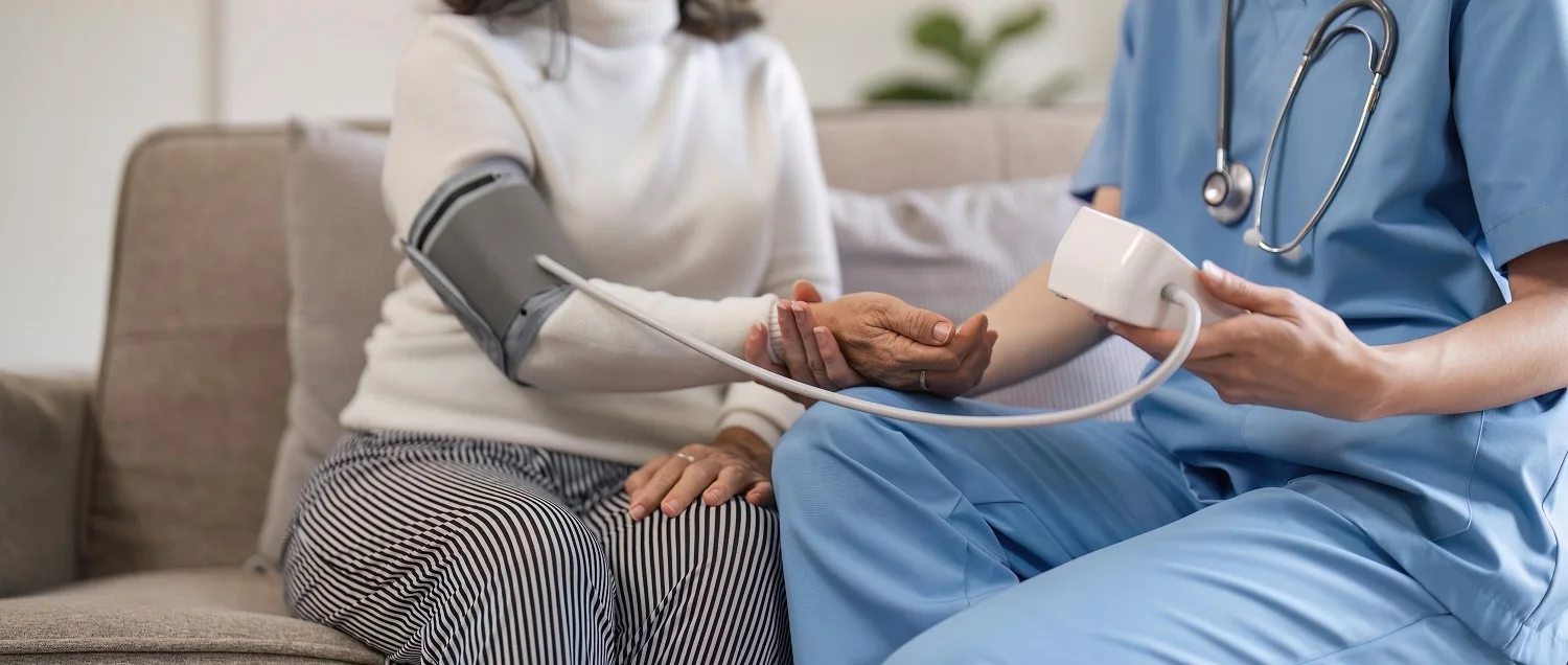 nurse measures blood pressure of elderly woman at home